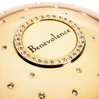 Gold cup of luxury fragrance  with 'Benevolence' branding and crystal embellishments
