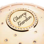Gold compact with 'Cherry Garden' text and rhinestone embellishments
