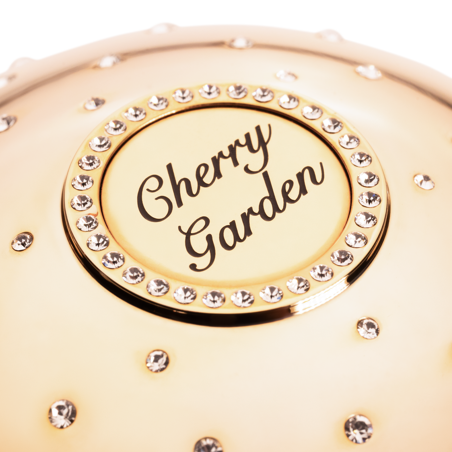 Gold compact with 'Cherry Garden' text and rhinestone embellishments